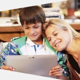 A boy and a lady on a computer smiling
